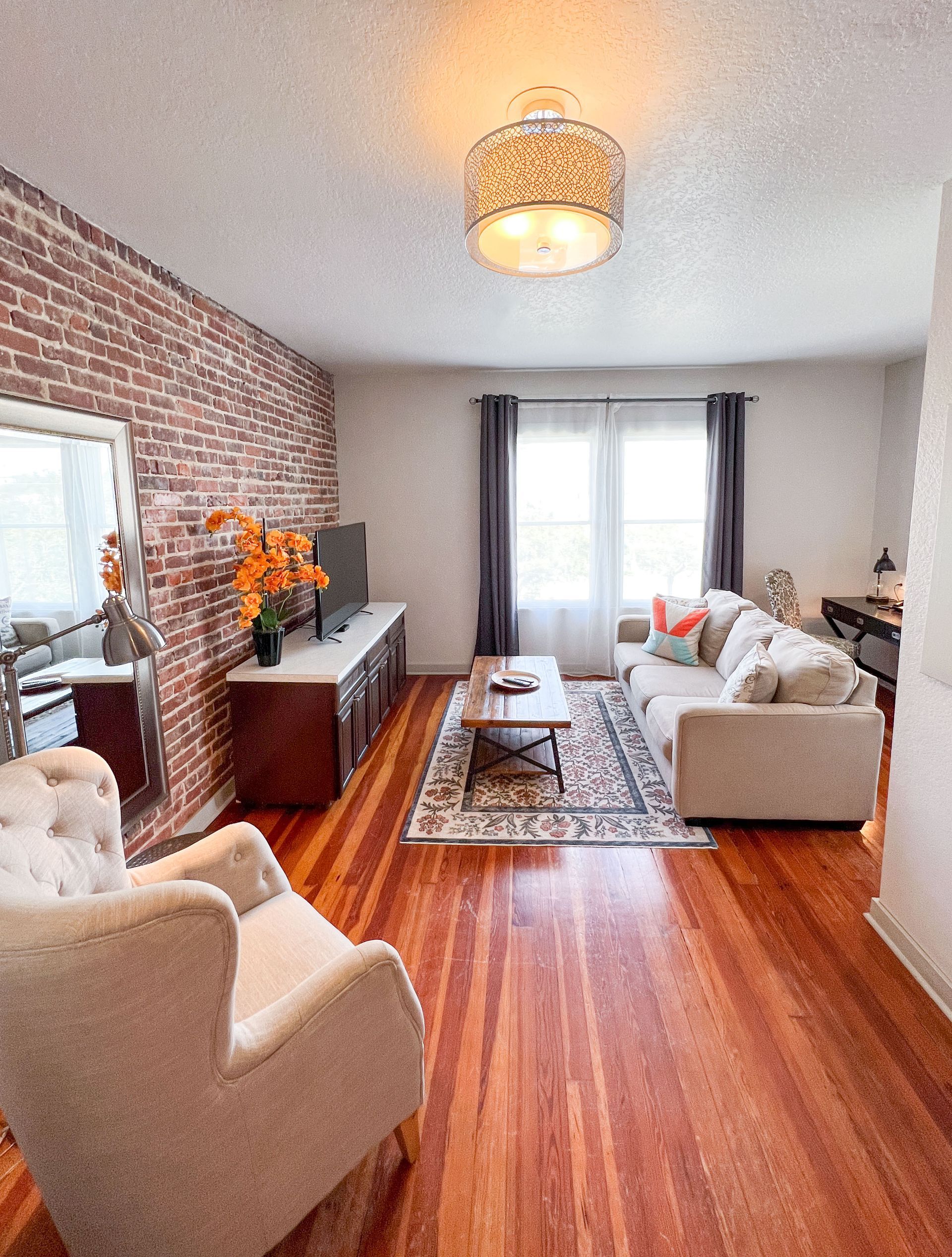 A living room with hardwood floors and a brick wall