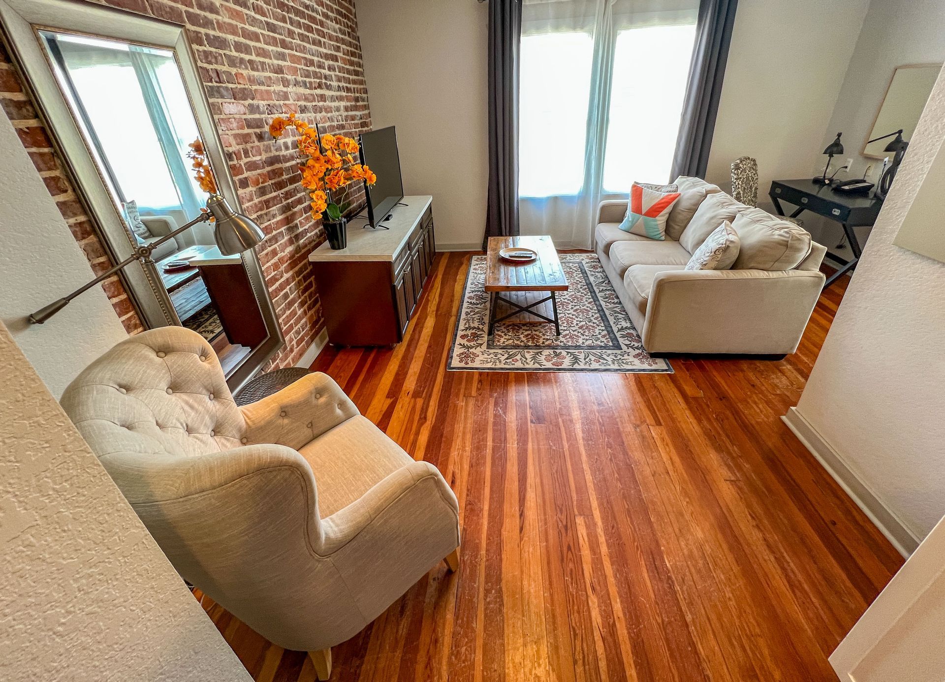 A living room with a couch , chair , coffee table and mirror.
