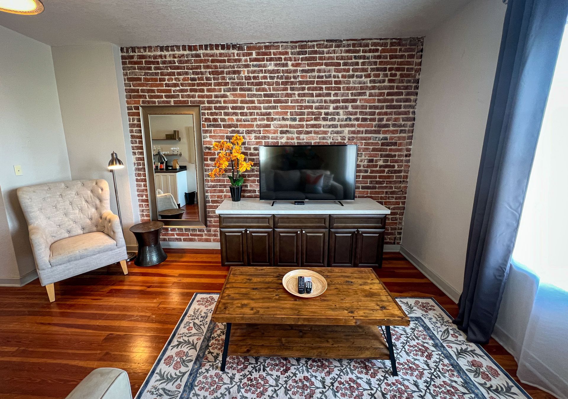 A living room with a brick wall and a flat screen tv.