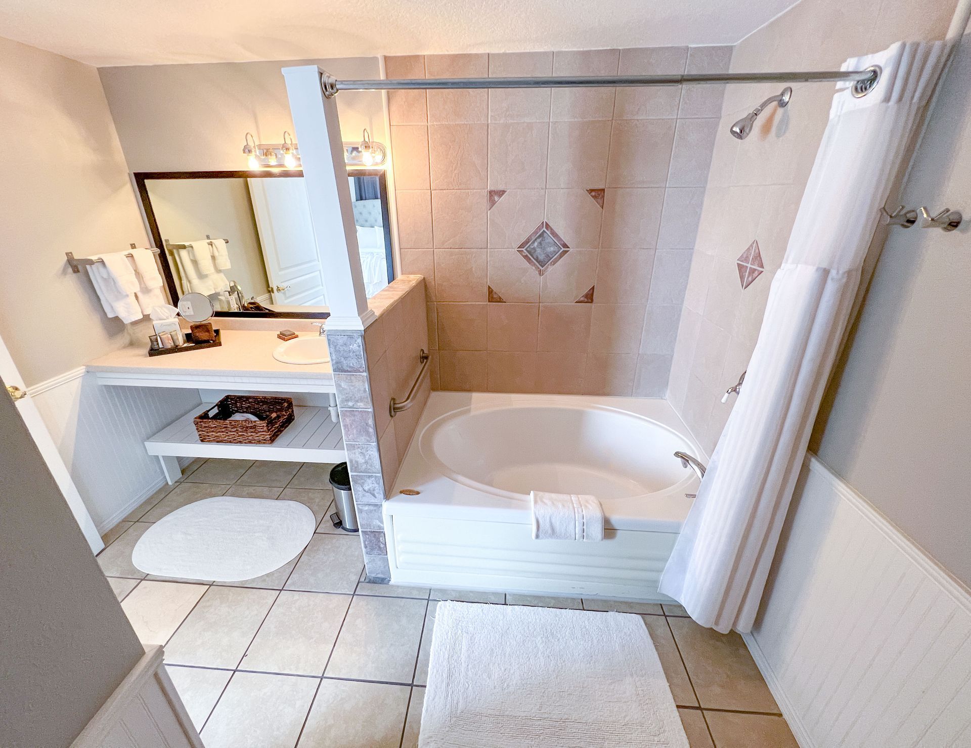 A bathroom with a tub , shower , sink and mirror
