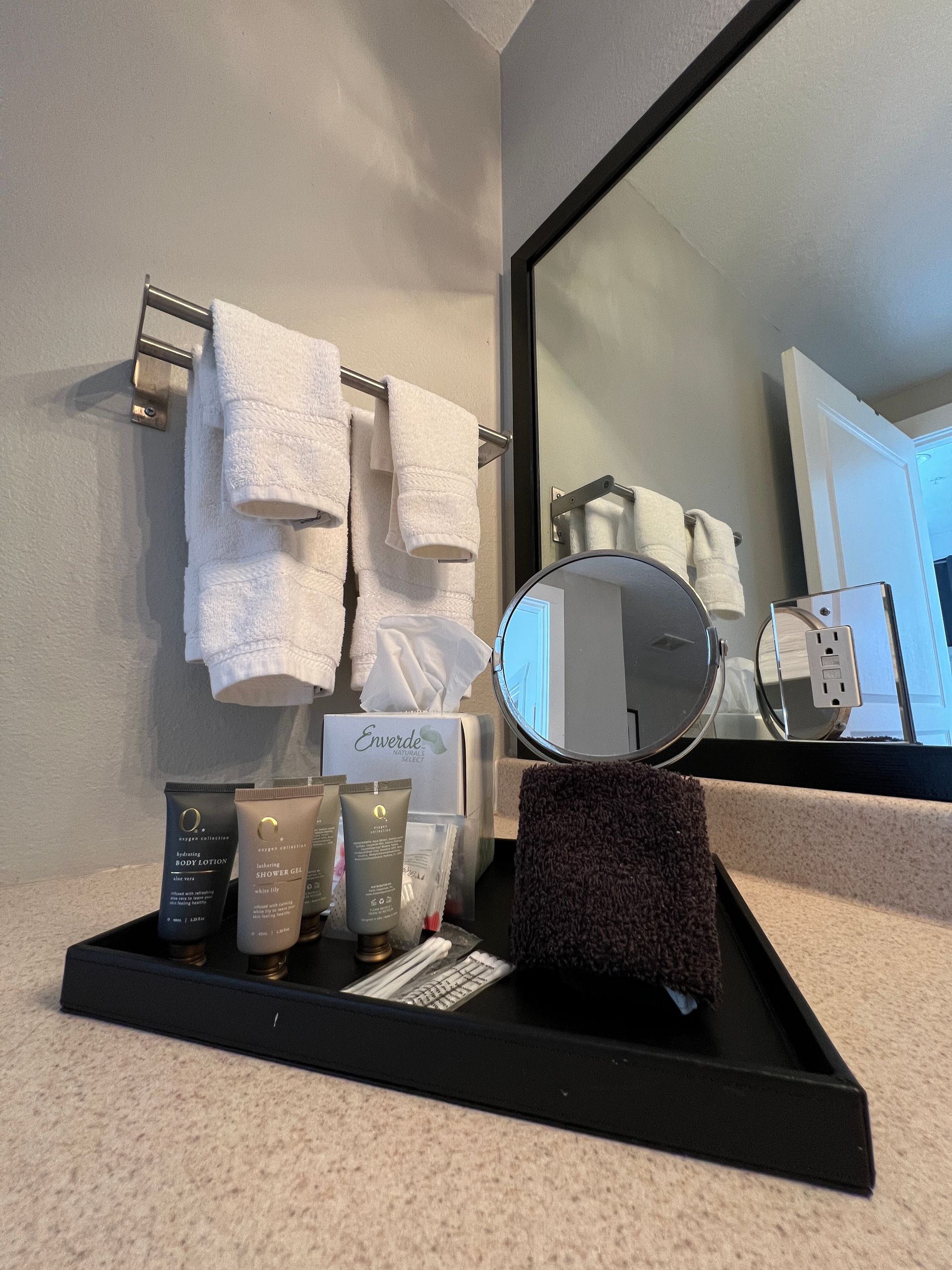 A bathroom with a tray of toiletries and a mirror
