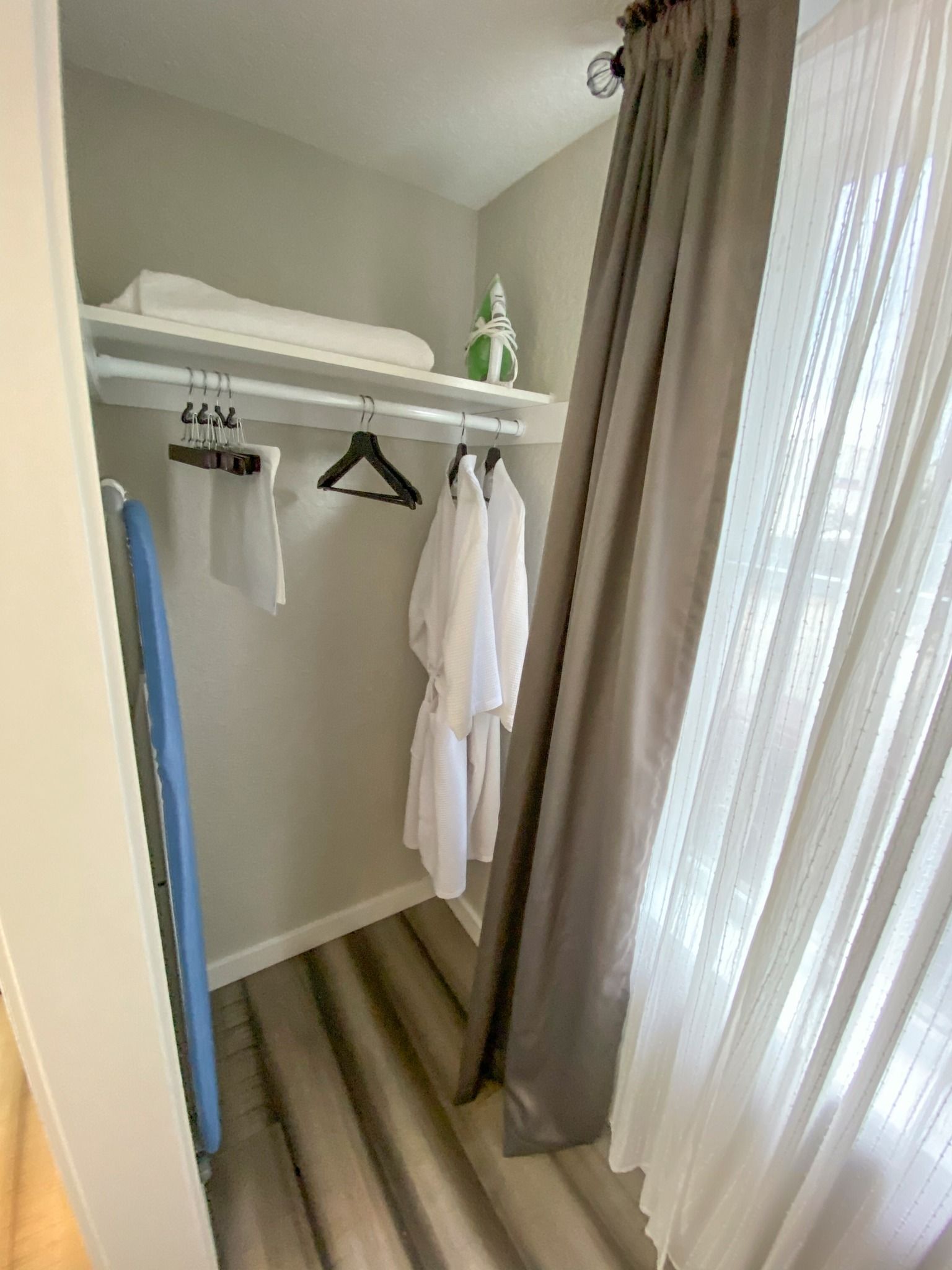 A walk in closet with clothes hanging on racks and curtains.