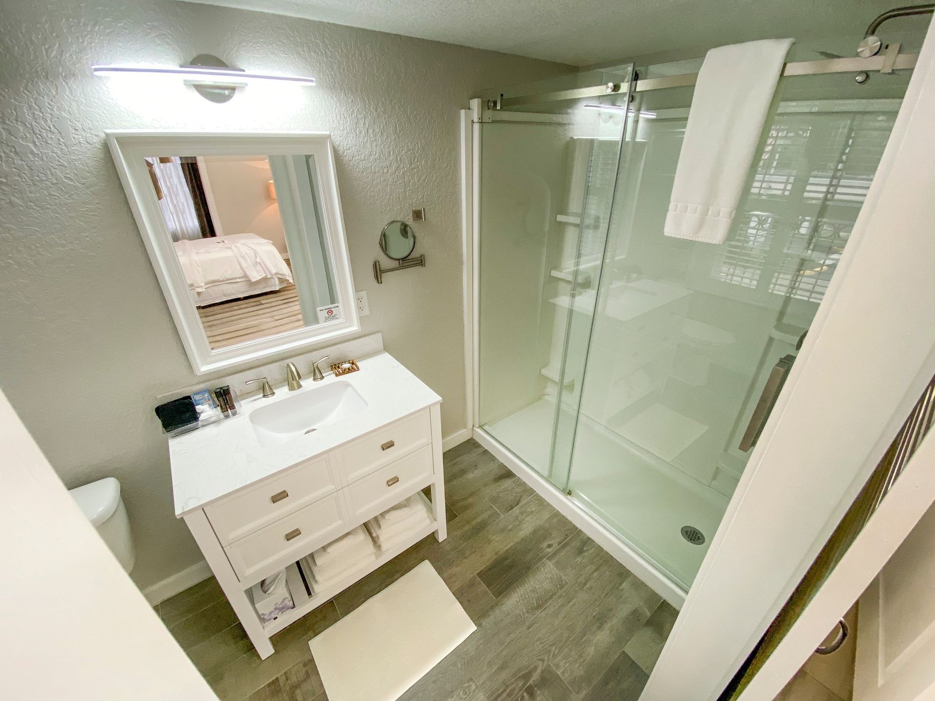 A bathroom with a sink , mirror , toilet and shower.