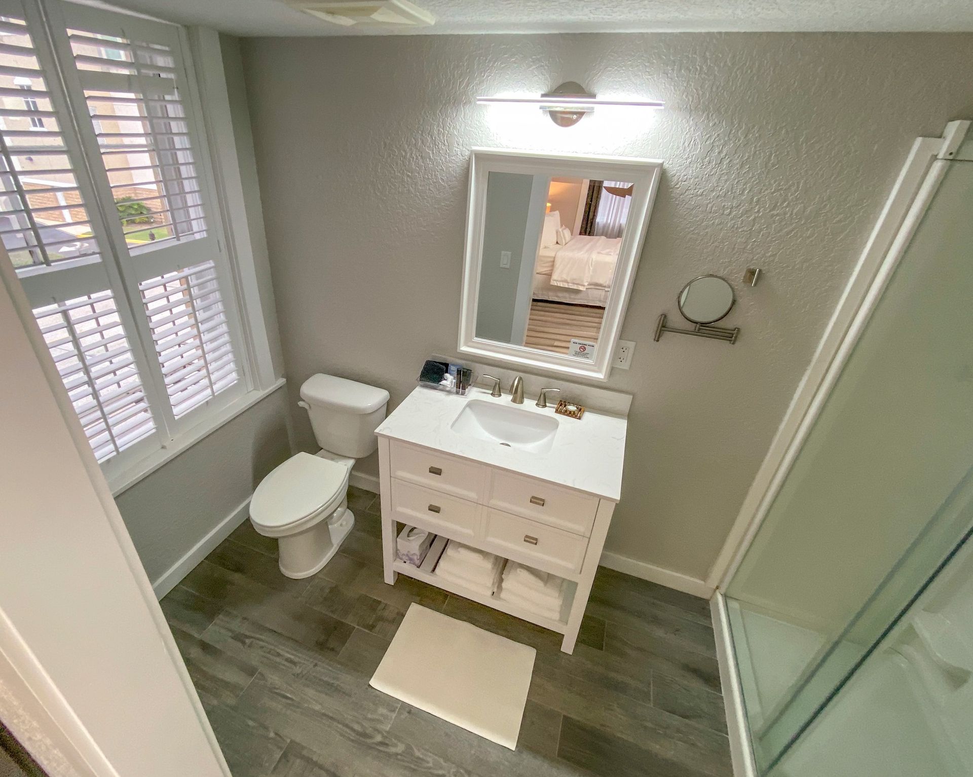A bathroom with a toilet , sink , mirror and shower.