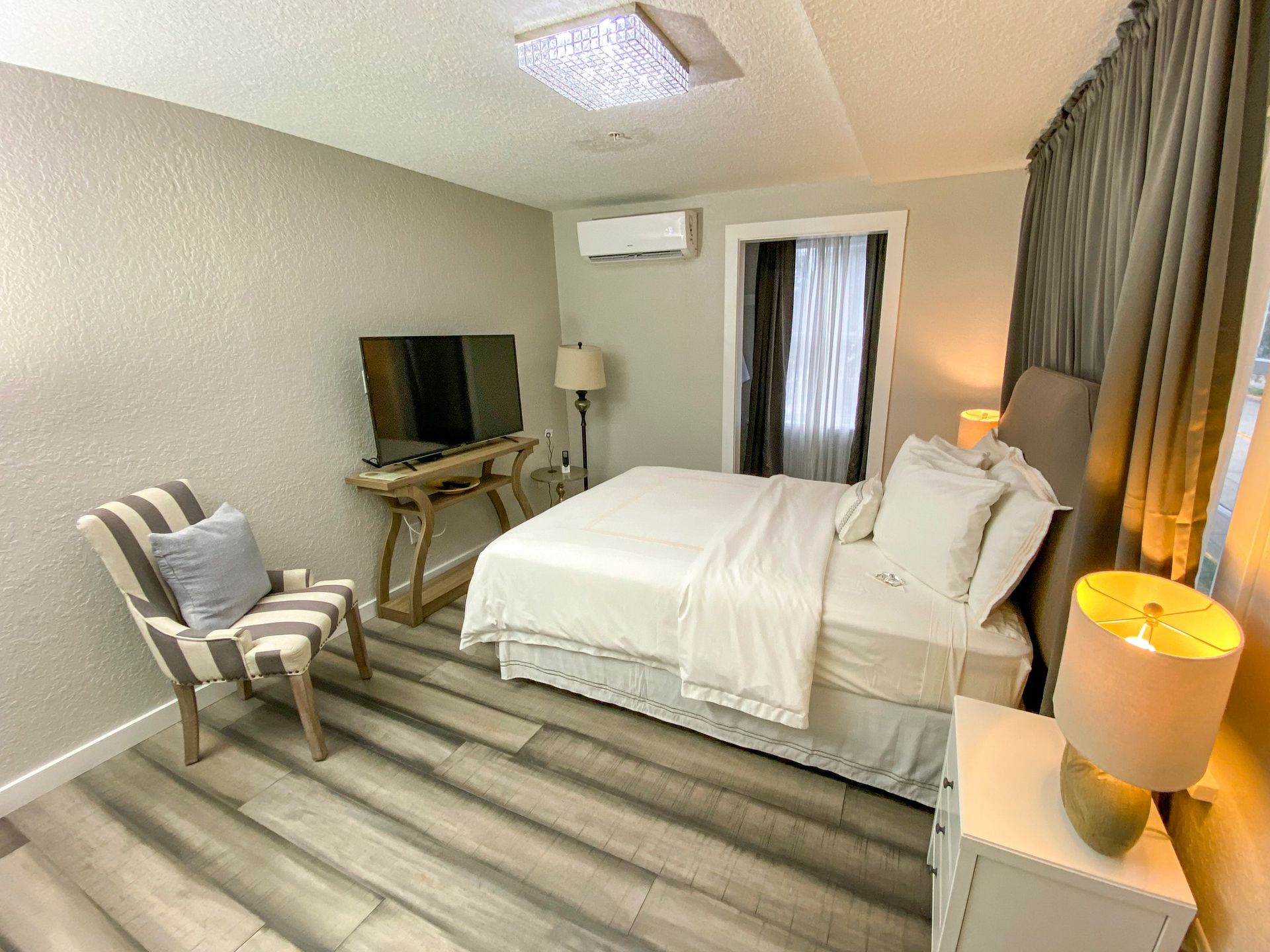 A bedroom with a bed , chair , nightstand and television.