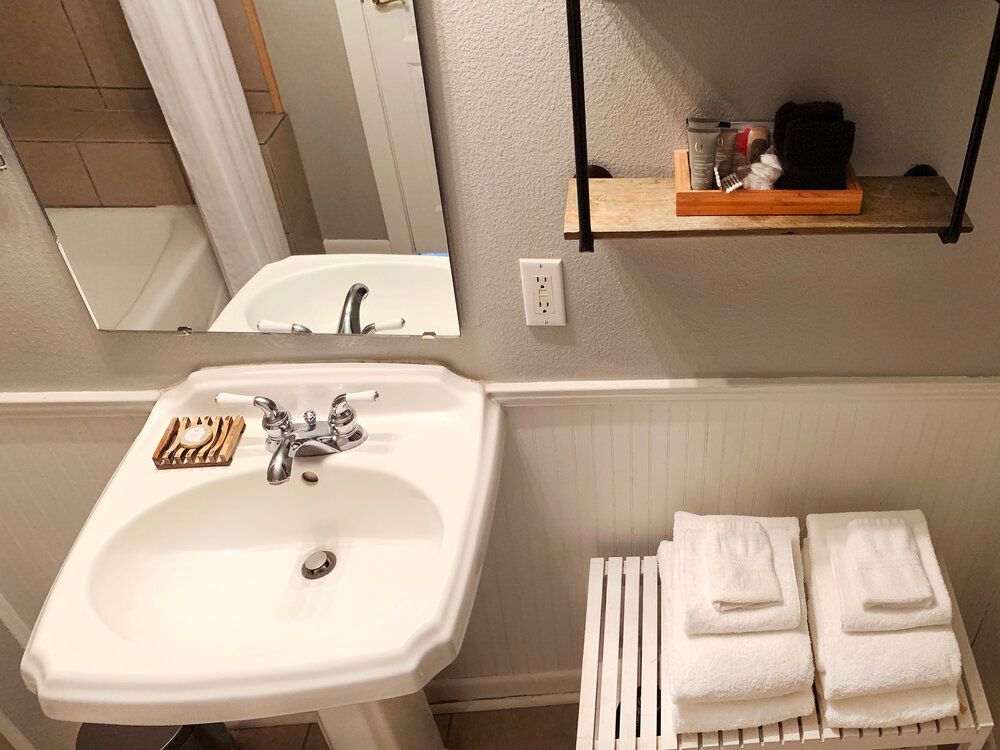 A bathroom with a sink , mirror and towels.