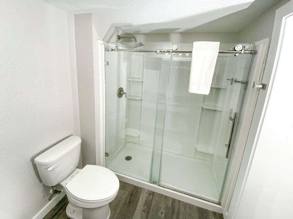 A bathroom with a toilet and a shower with sliding glass doors.