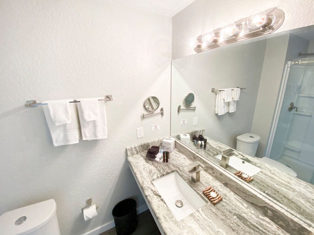 A bathroom with two sinks , a toilet , and a large mirror.
