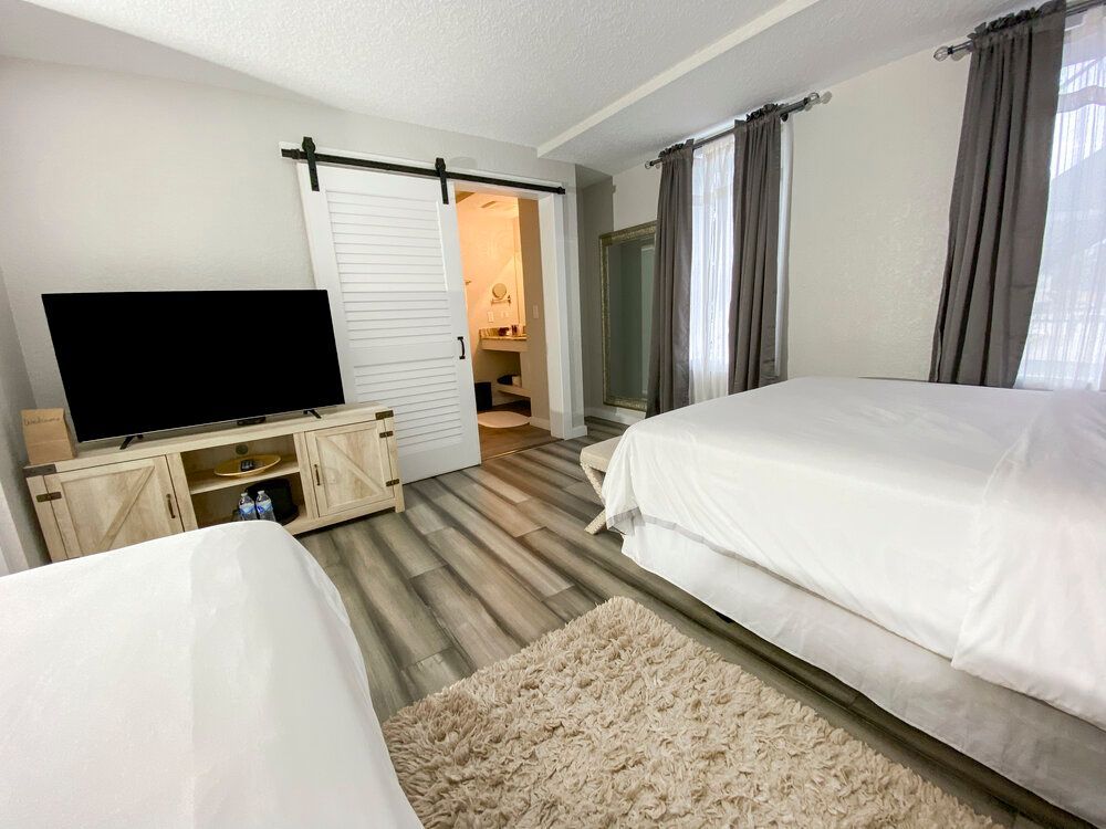 A bedroom with two beds and a flat screen tv.