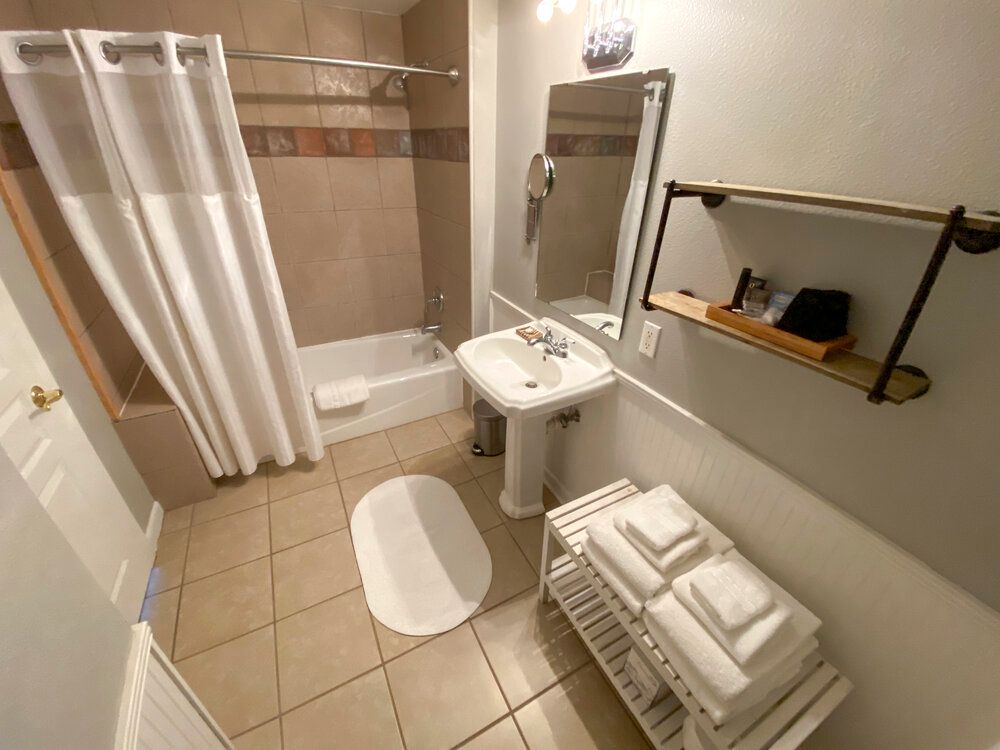 A bathroom with a sink , tub , mirror and towels.