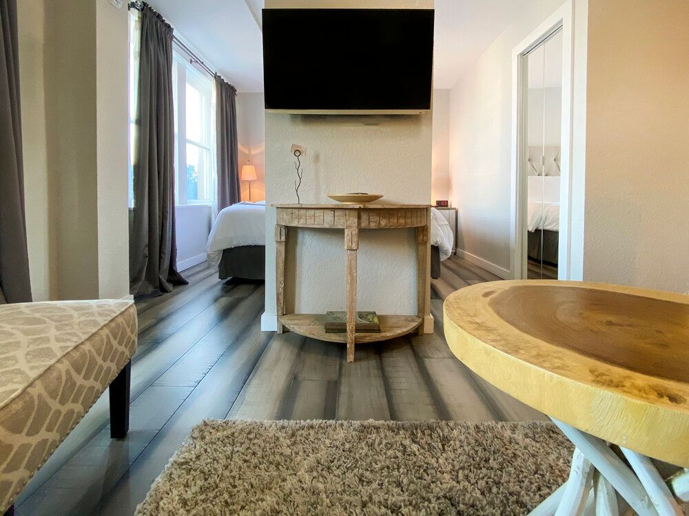 A living room with a wooden table and a flat screen tv on the wall.