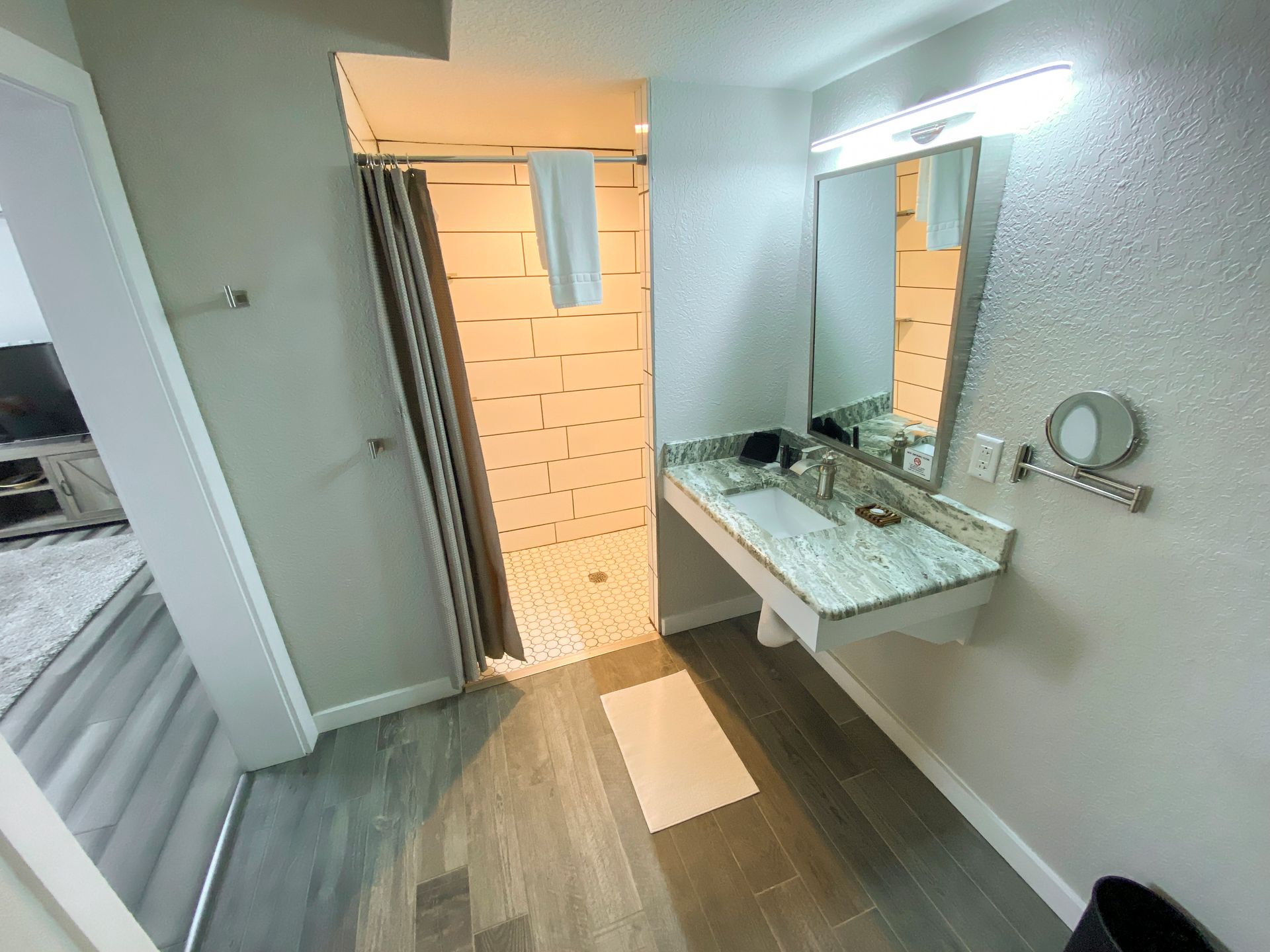 A bathroom with a sink , mirror and shower.