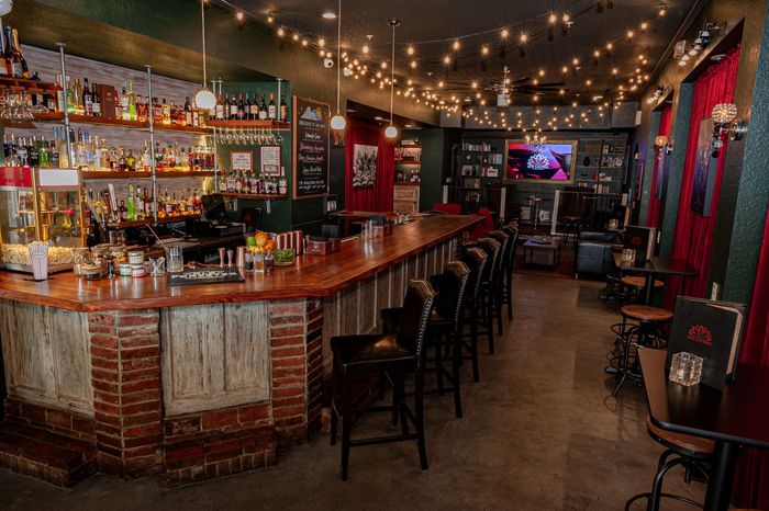 There is a long bar in the middle of the room with tables and chairs.
