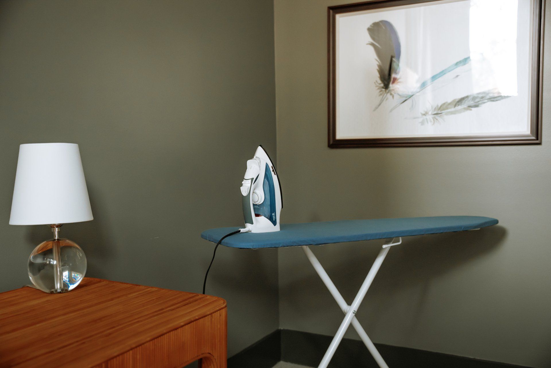 An ironing board with a picture on the wall above it