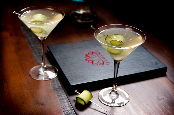 Two martini glasses are on a table next to a menu