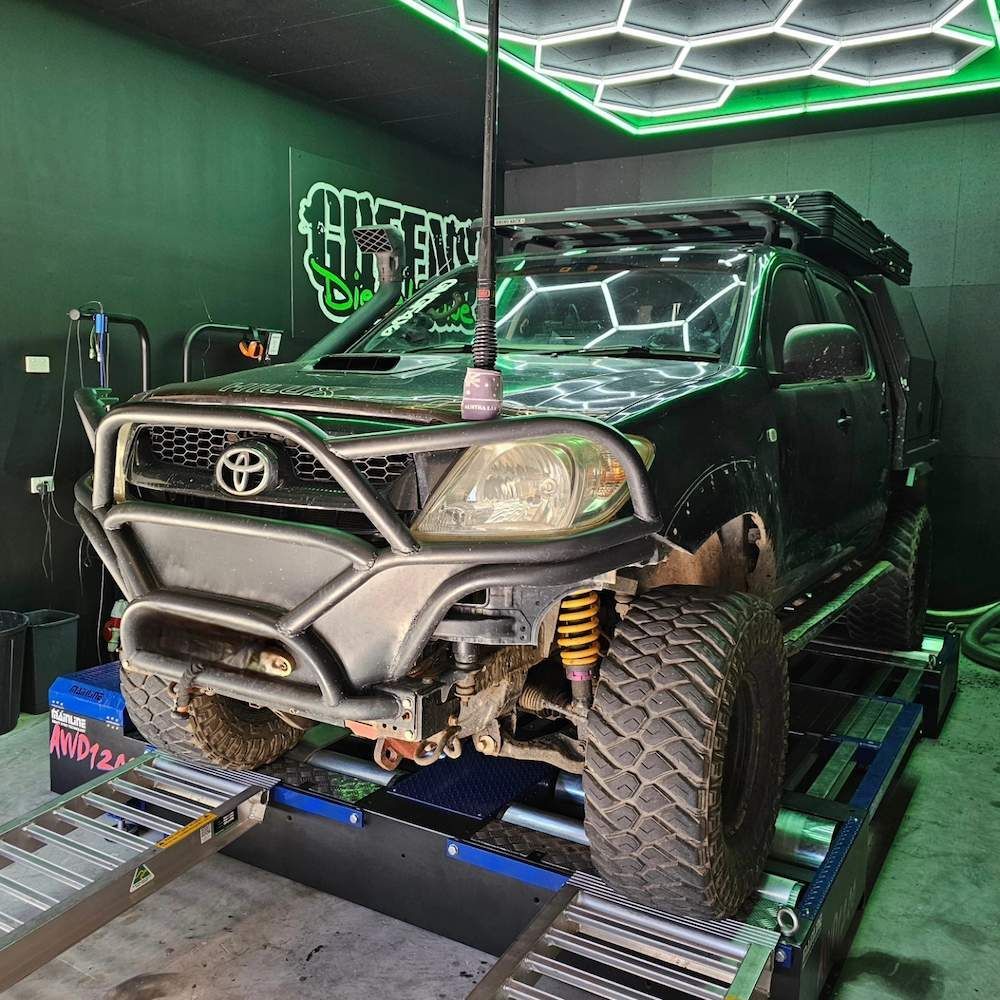Black Off-road Toyota Hilux on a Dyno, in a Garage. It Has a Bull Bar — Greens Diesel Tune in Campbelltown, NSW