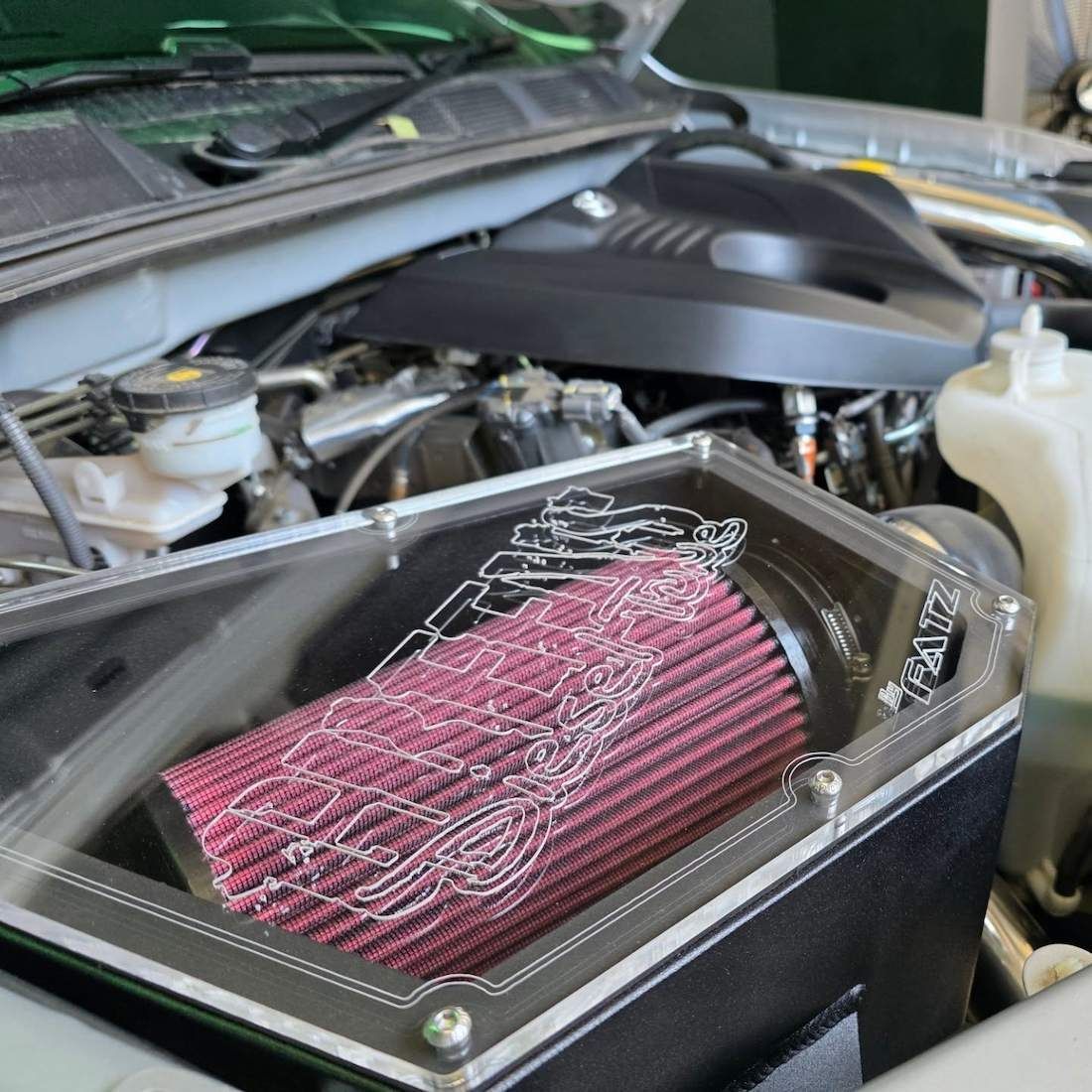 Red Air Filter in a Clear and Black Housing, Inside a Car's Engine Bay — Greens Diesel Tune in Smeaton Grange, NSW