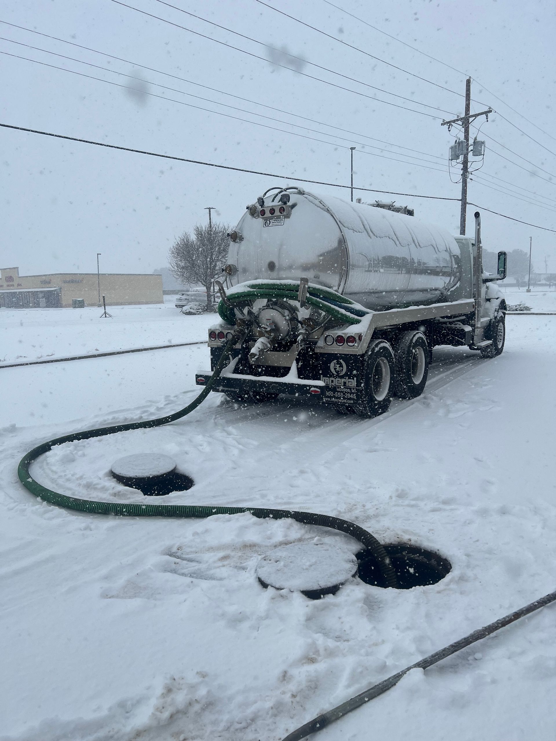 A septic tank truck pumping waste in a snowy environment.