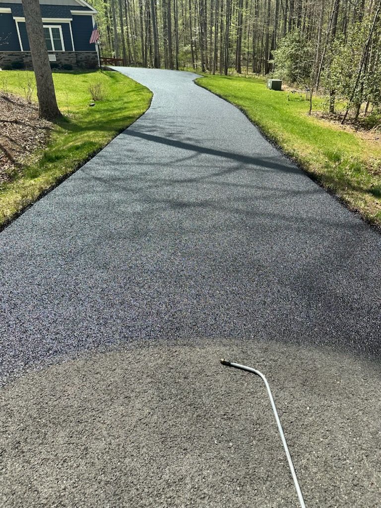 Gravel path curving through a wooded area beside a house, with a white cane in the foreground.