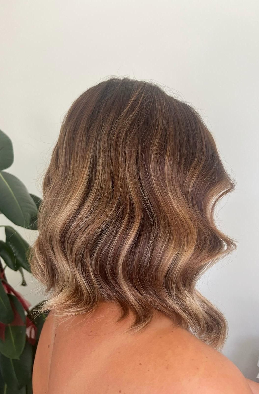 Donna con capelli castani ondulati con riflessi biondi, acconciati a caschetto.