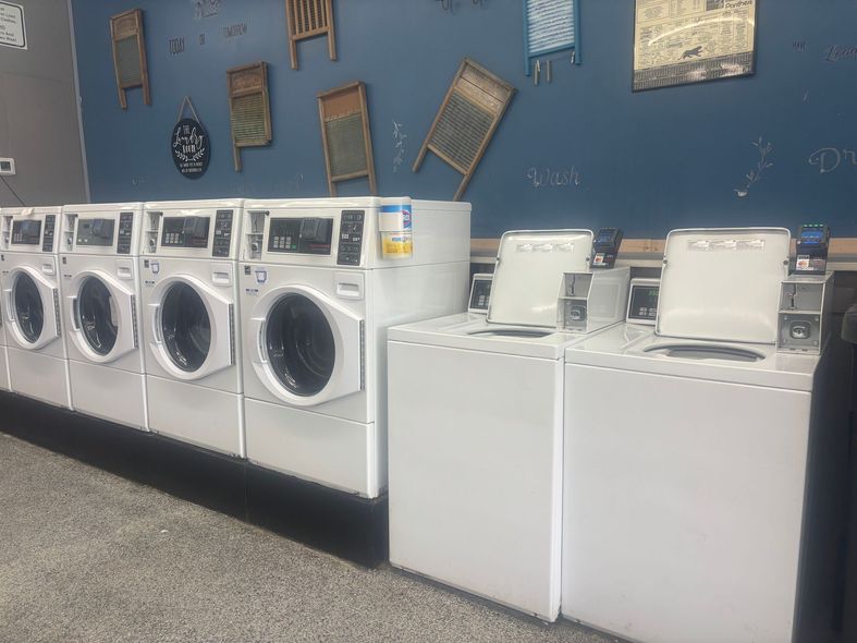 A row of washing machines filled with clothes in a laundromat.