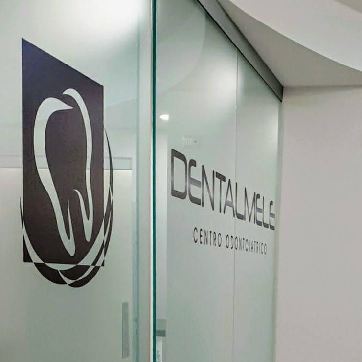 Parete in vetro della clinica odontoiatrica con logo a forma di dente e insegna