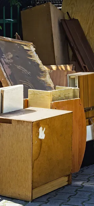 Pile of discarded wooden furniture and boards on a pavement.