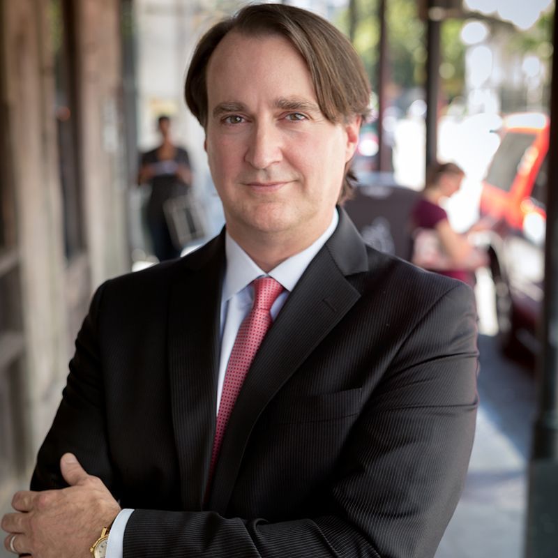 A man in a suit and tie is standing with his arms crossed