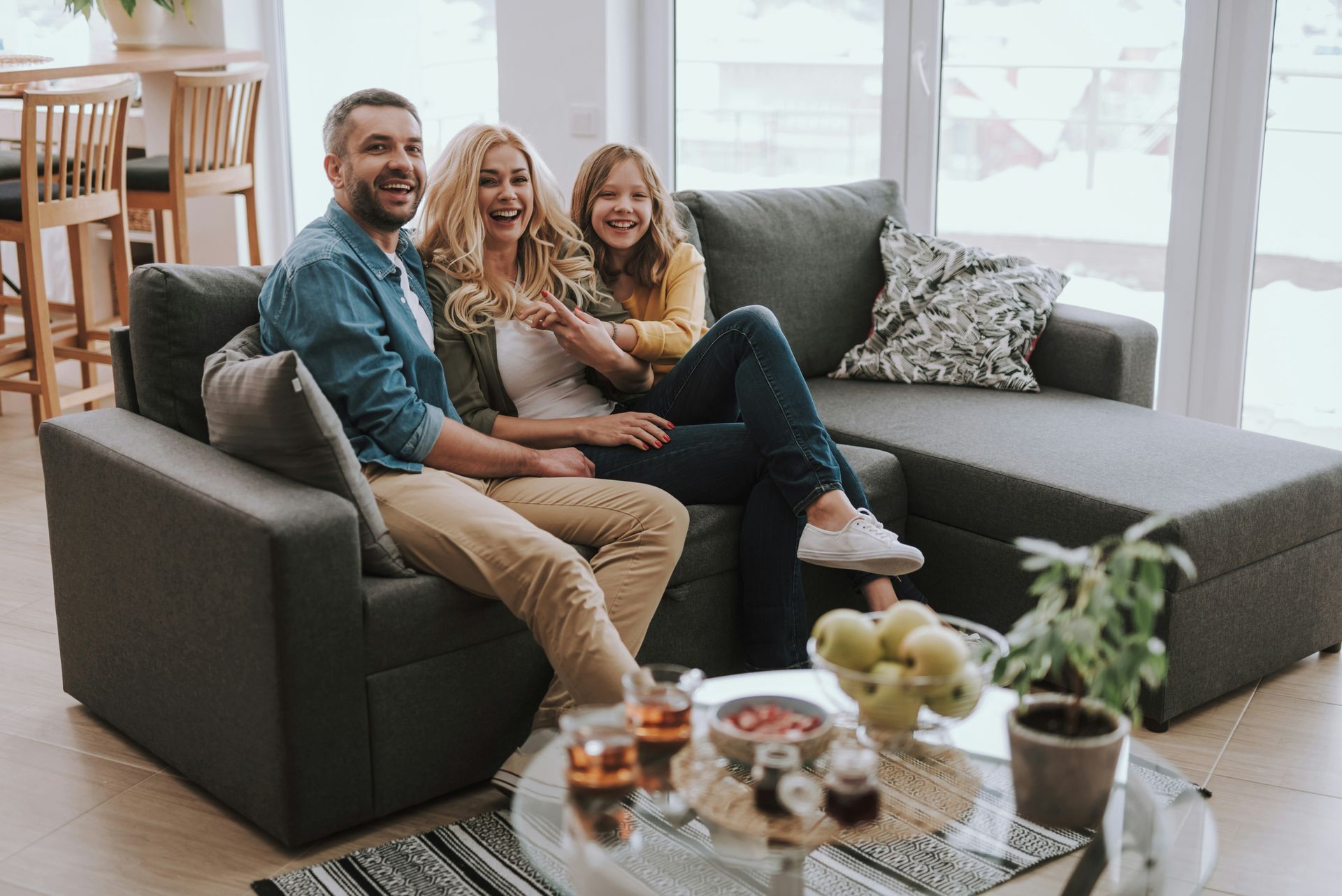 A family is sitting on a couch in a living room.