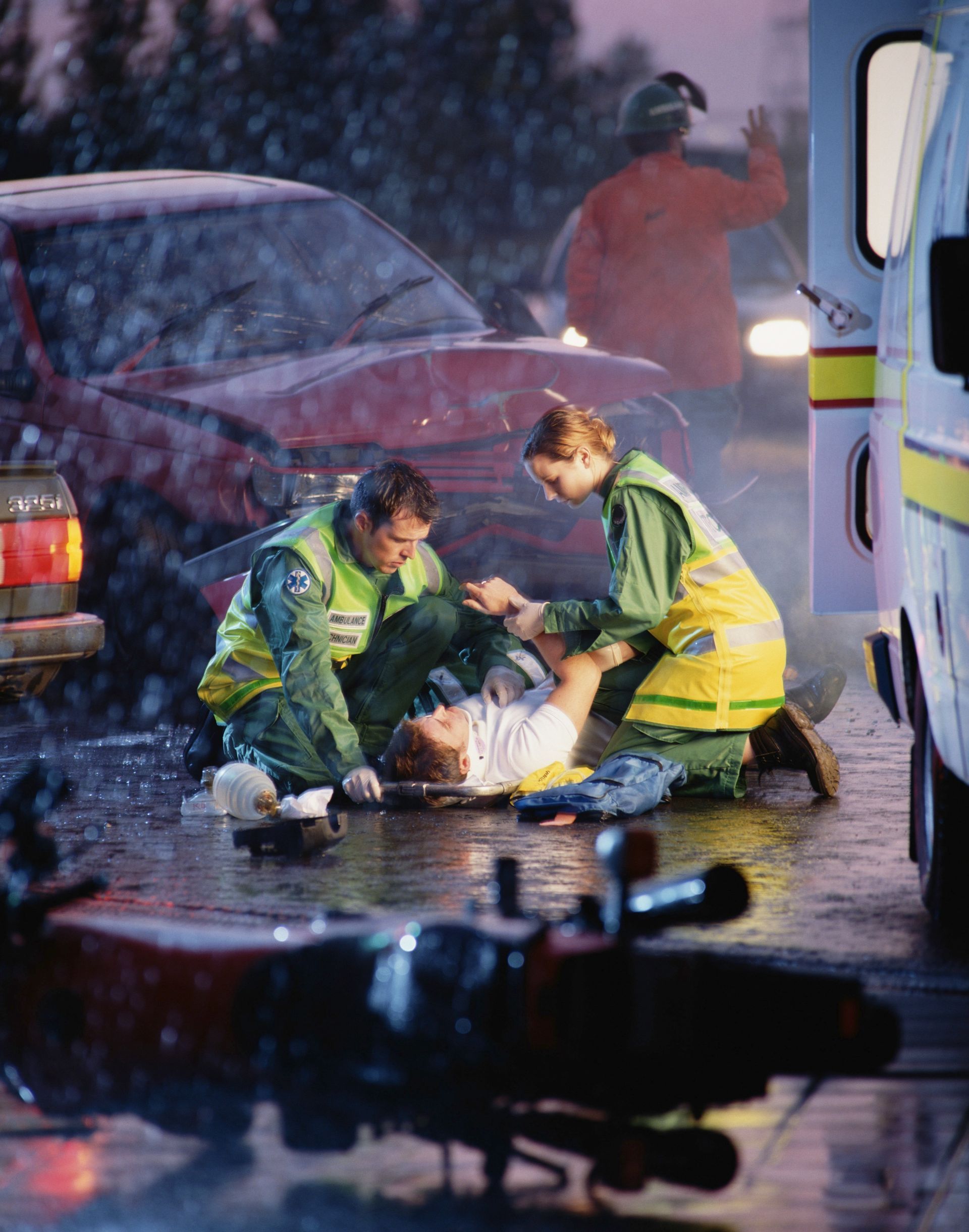 A man is laying on the ground being helped by two paramedics