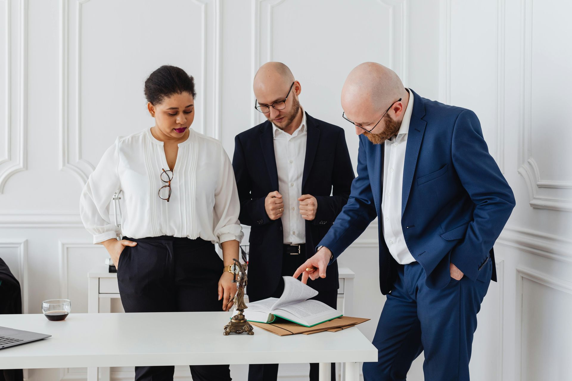A group of people are standing around a table looking at a book.