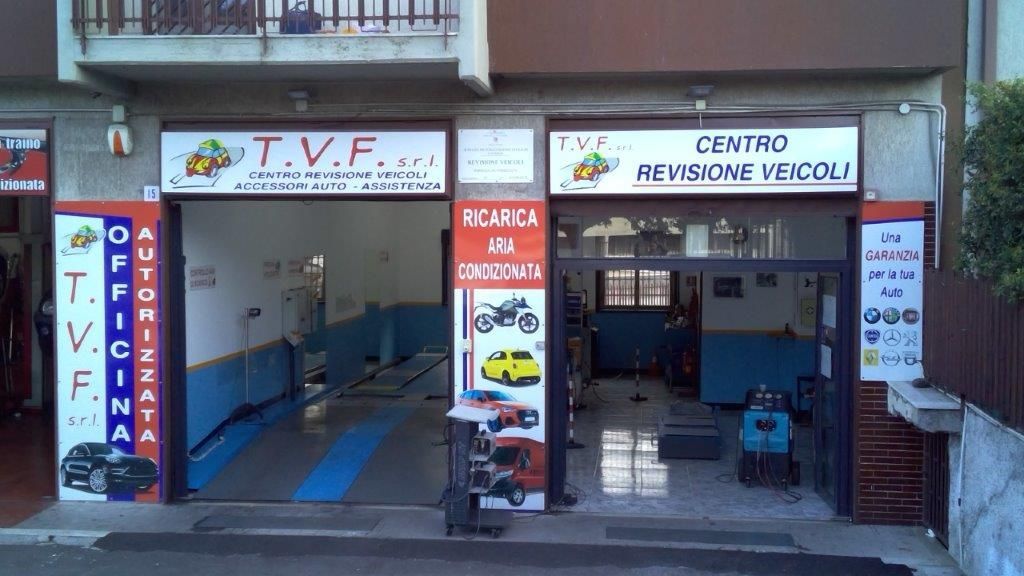 Interno dell'officina con attrezzature e veicoli per la riparazione di camion. Gru gialla in alto.