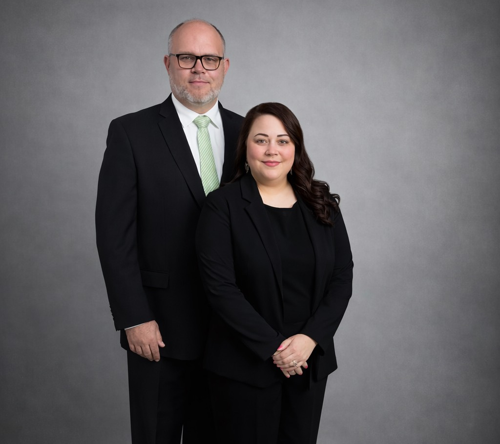 Family portrait: four people in black suits against a black background.