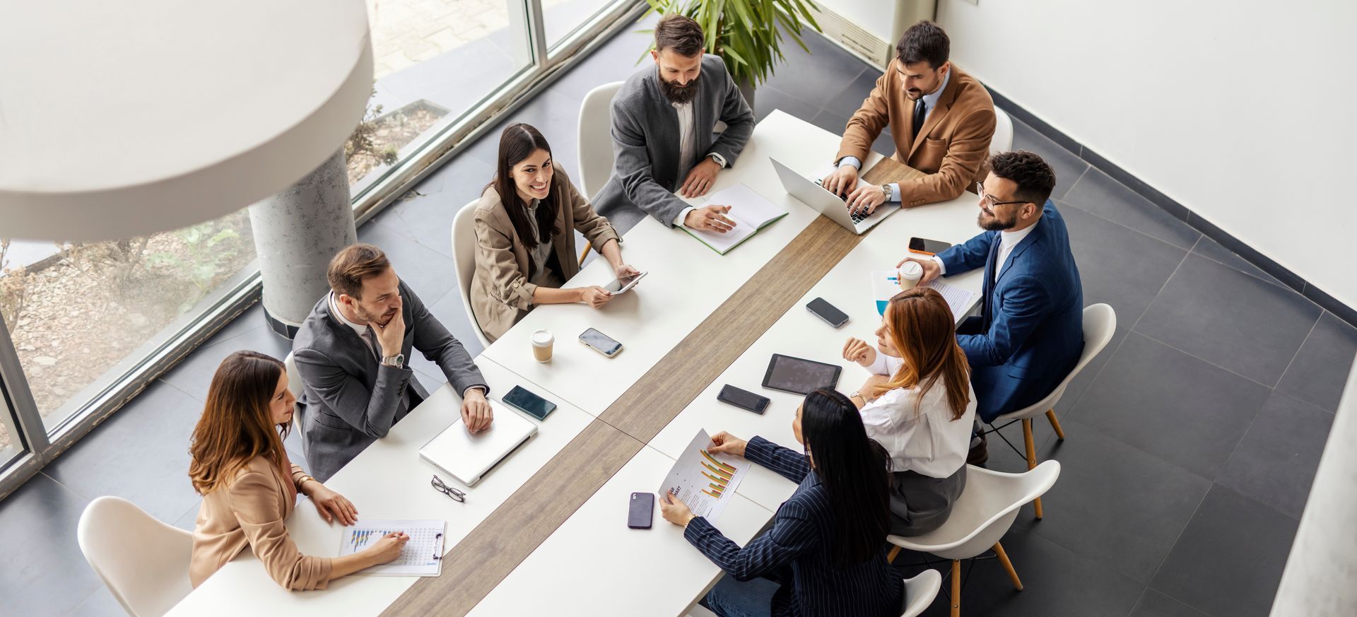 Businesspeople in suits at a conference table, looking at documents and laptops. Bright, modern office space.Businesspeople in suits at a conference table, looking at documents and laptops. Bright, modern office space. Businesspeople in suits at a conference table, looking at documents and laptops. Bright, modern office space.