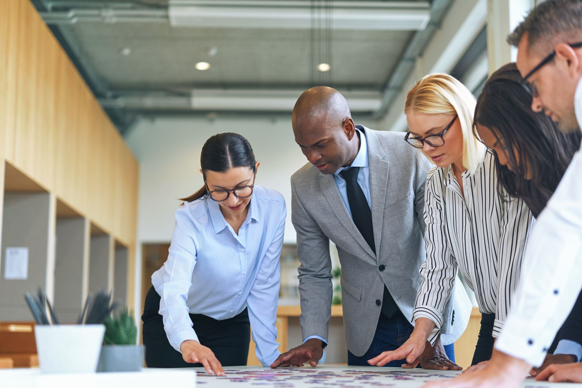 Business team gathered around a table, collaborating on a project. They are looking at a document. Business team gathered around a table, collaborating on a project. They are looking at a document.