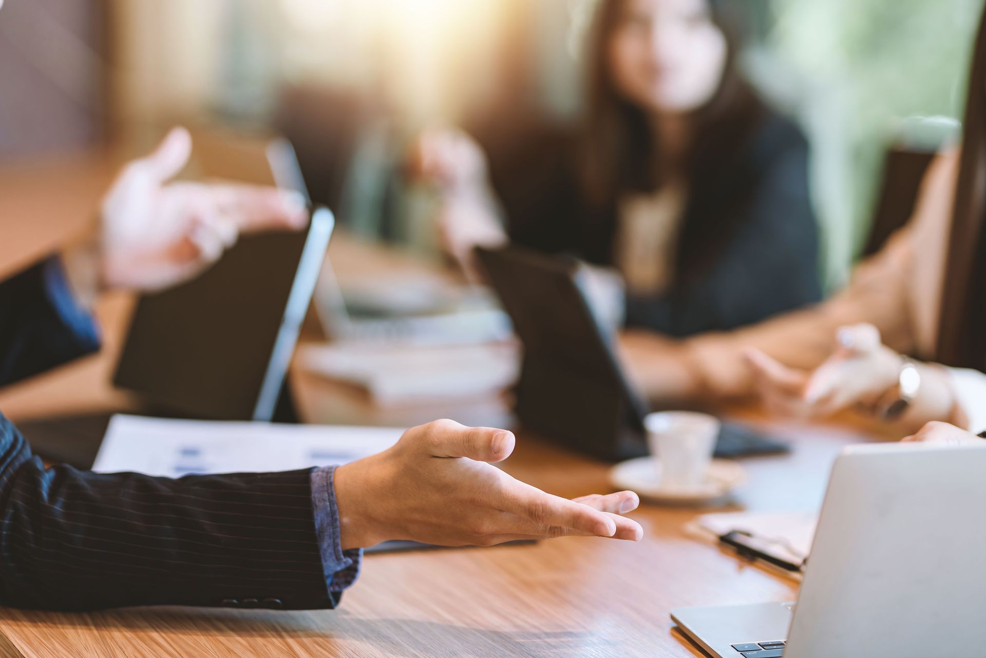 People in a business meeting around a table, using laptops and discussing ideas. People in a business meeting around a table, using laptops and discussing ideas.