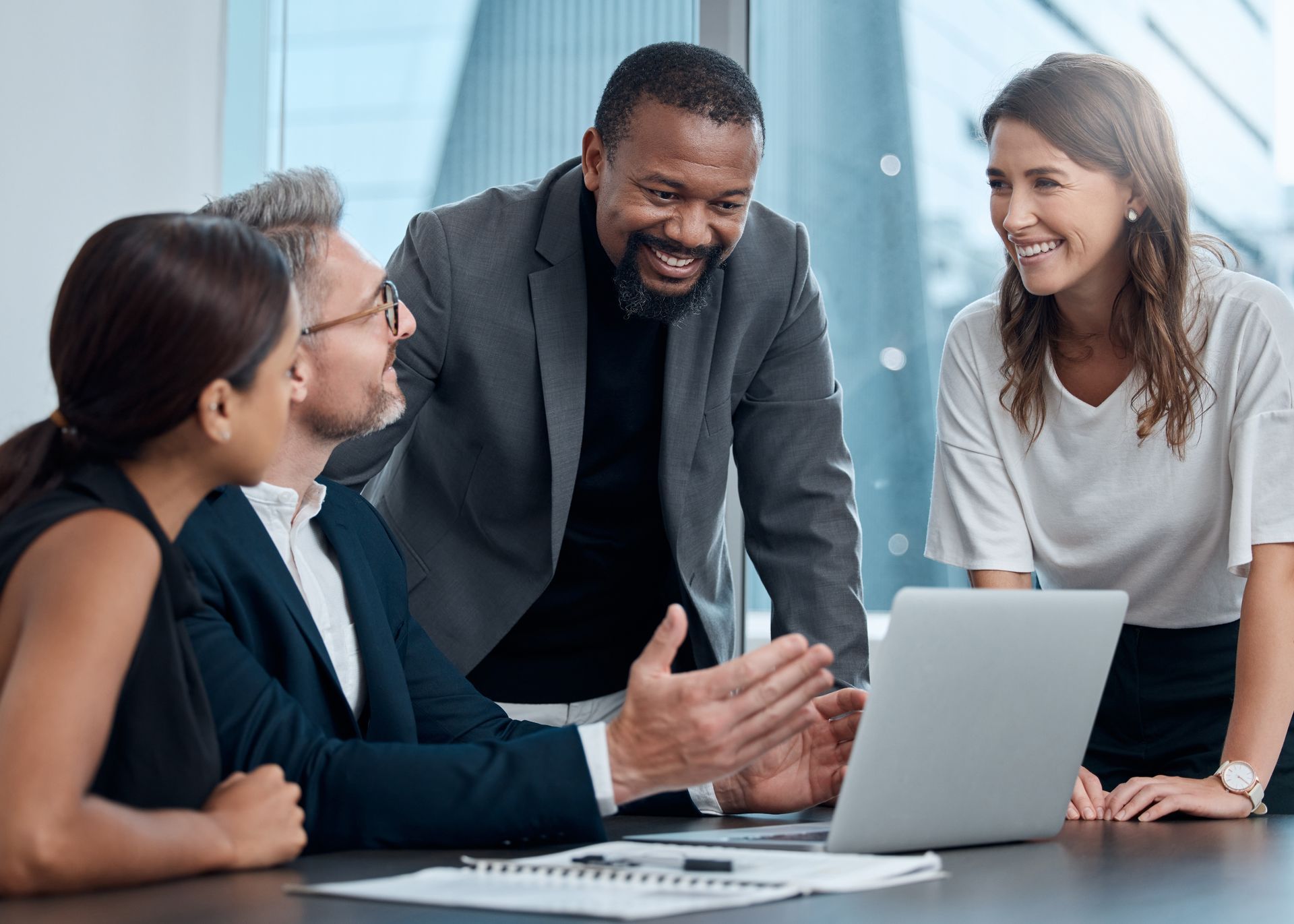 Businesspeople gather around a laptop, discussing a project in an office setting. Businesspeople gather around a laptop, discussing a project in an office setting.