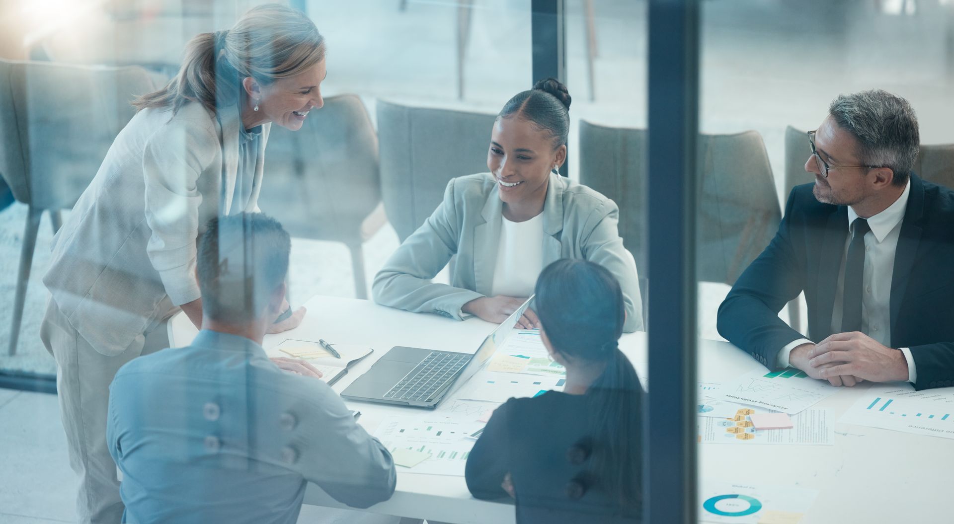 Business team in a meeting, around a table, discussing documents and laptop, in an office setting. Business team in a meeting, around a table, discussing documents and laptop, in an office setting.