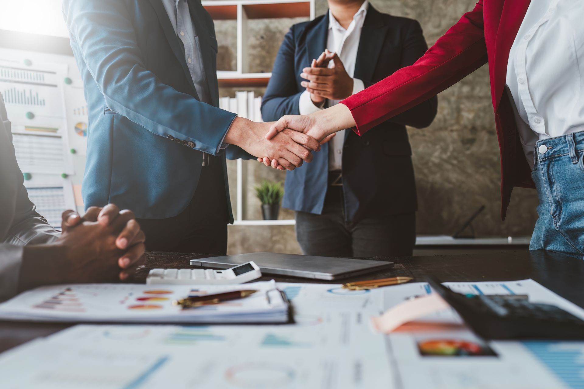 Business people shaking hands over a table with financial documents. Business people shaking hands over a table with financial documents.