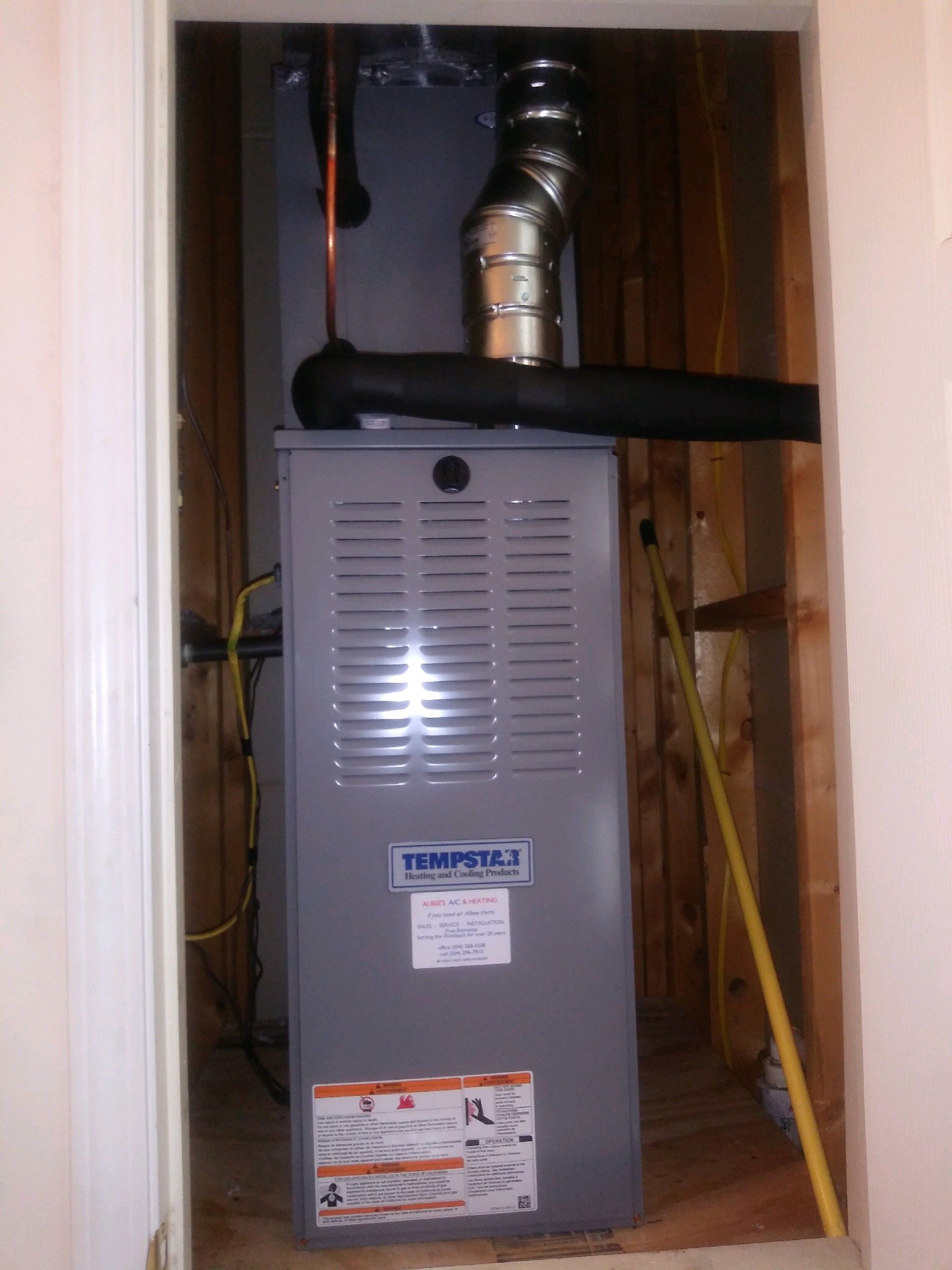 An air conditioner is installed in a closet next to a measuring tape.