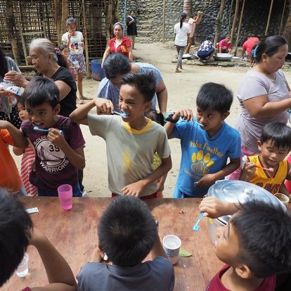 A group of children are brushing their teeth at a table
