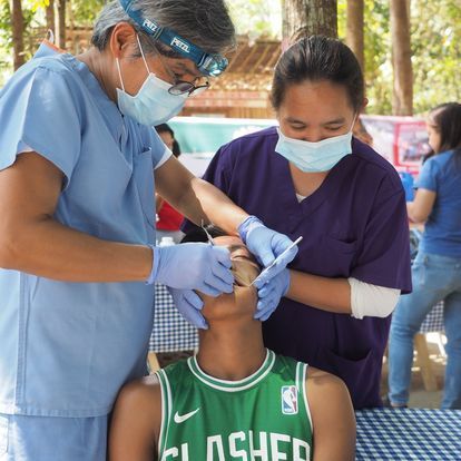 A man wearing a green flasher jersey is getting his teeth examined