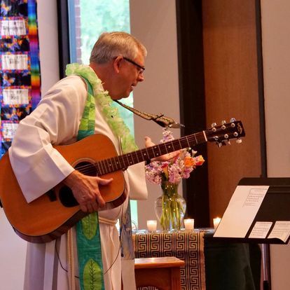 A man in a white robe is playing a guitar and singing into a microphone