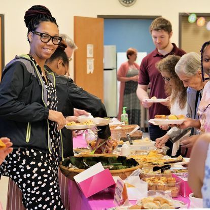 A group of people standing around a table with plates of food