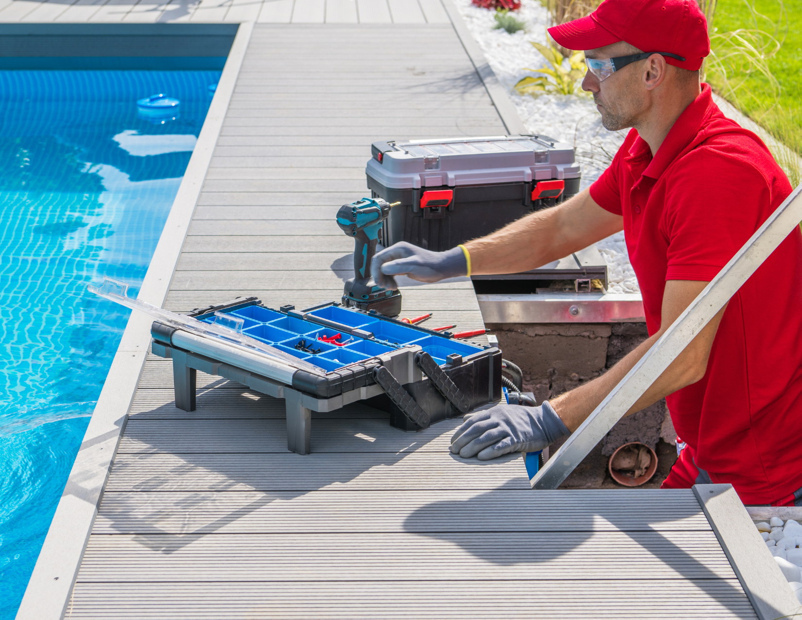 A man in a red shirt is working on a swimming pool.