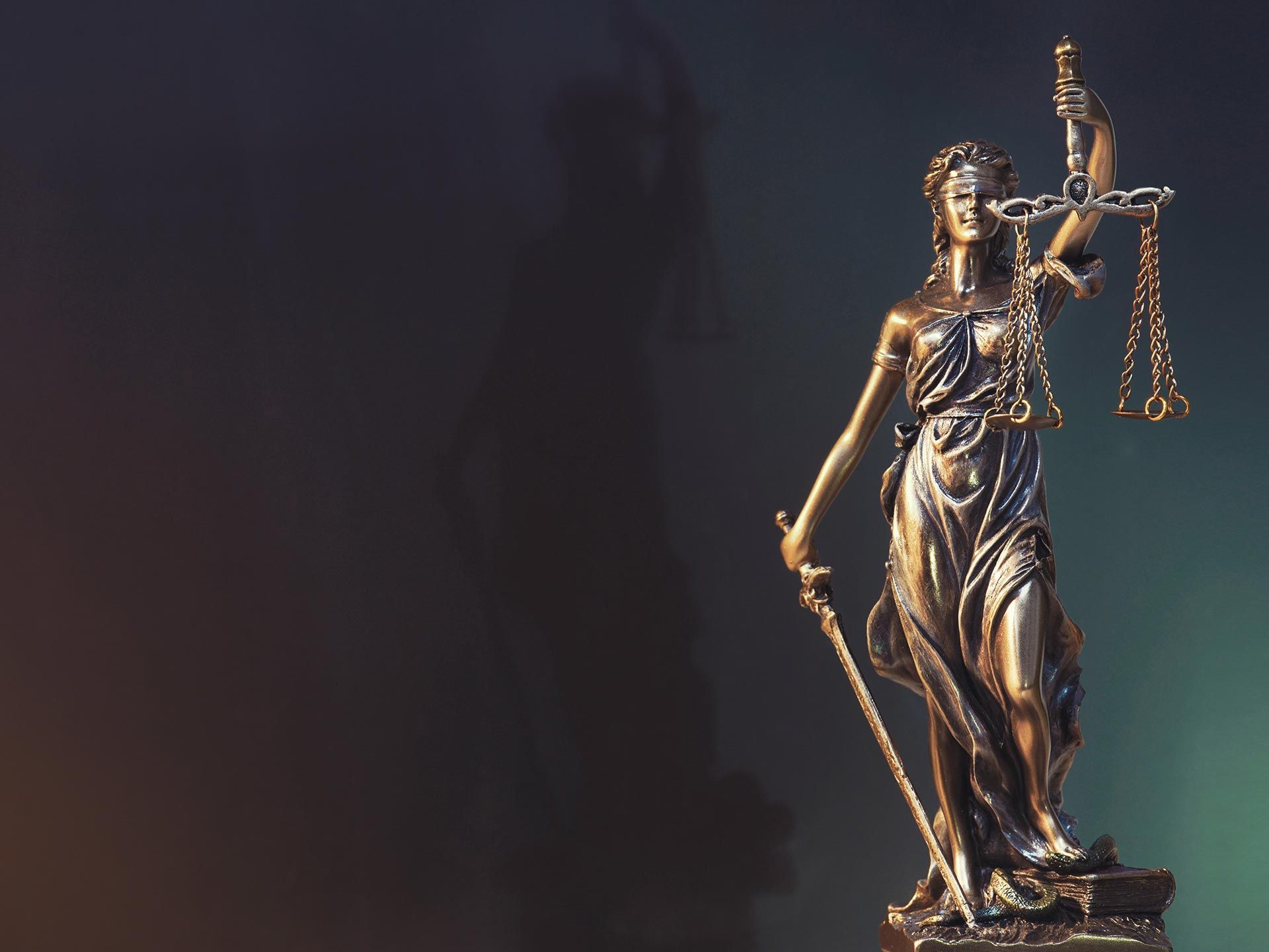 Statue of Lady Justice holding scales and sword, set against a dark background.