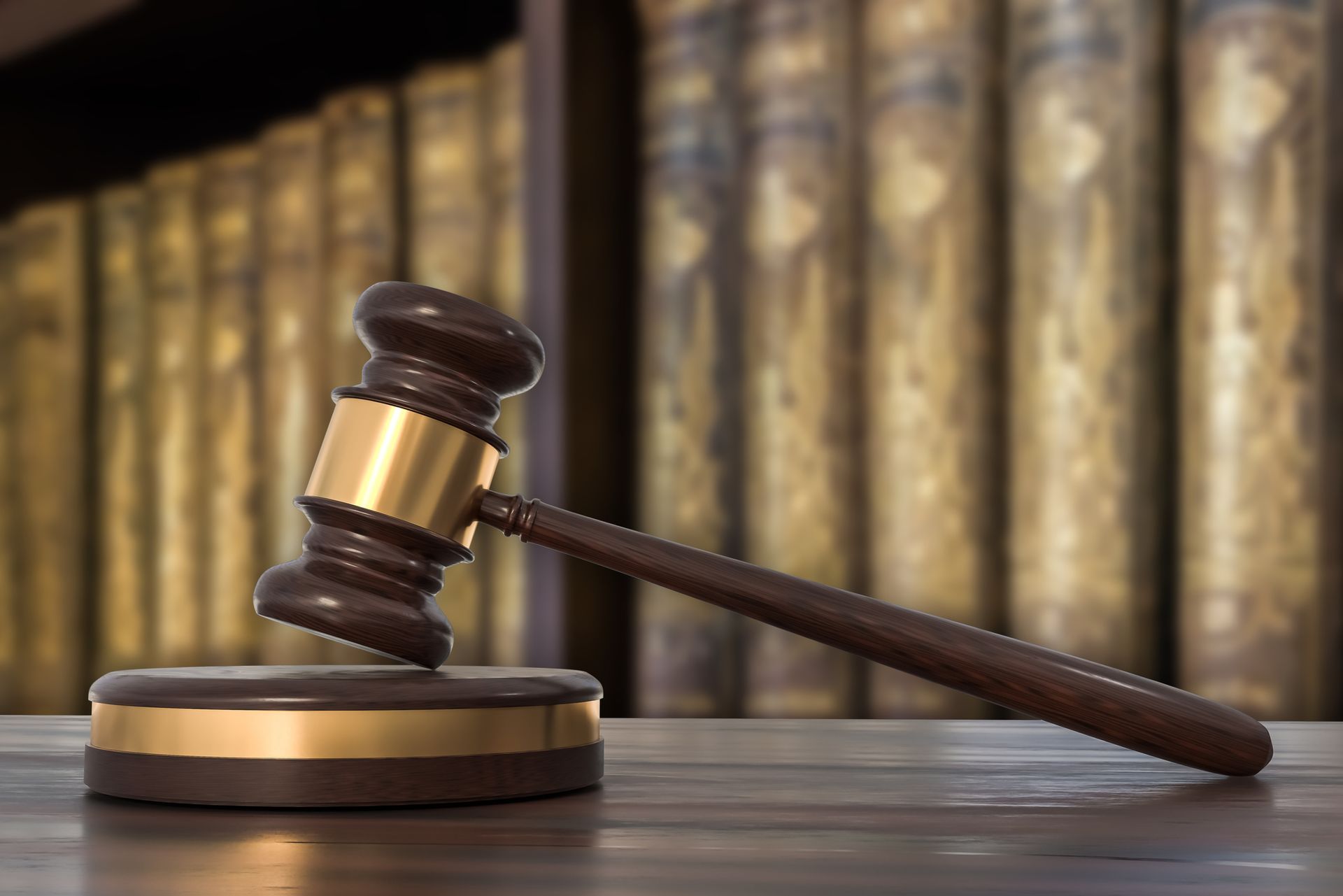 Wooden gavel on desk in front of law books for legal services and courtroom representation needs.