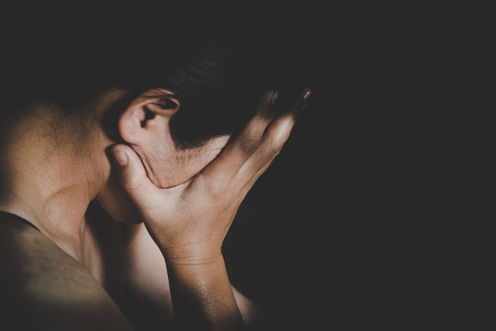 a man is covering his face with his hands in a dark room .