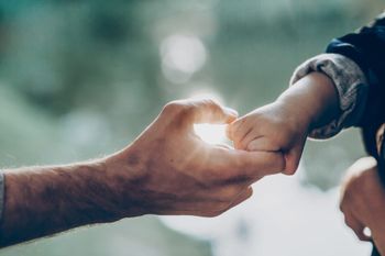 a man is holding a baby 's hand in a heart shape .