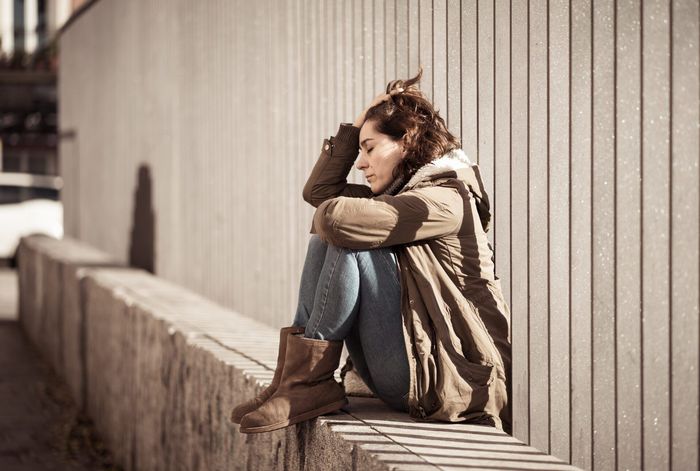 a woman is sitting on a bench with her head in her hands .